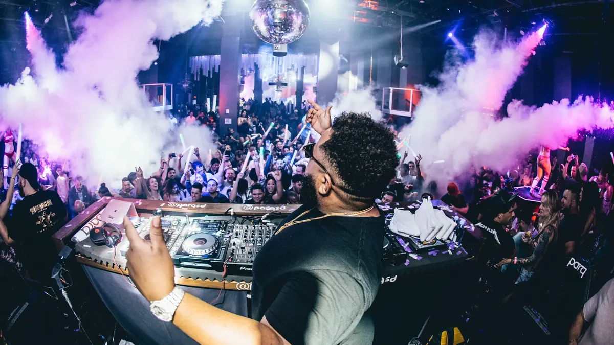 A DJ performing for a crowded nightclub dance floor