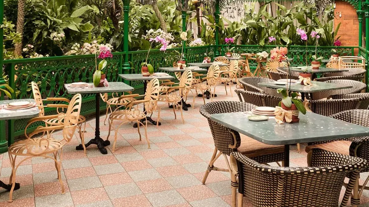 Tables and wicker chairs in a plant-filled outdoor cafe